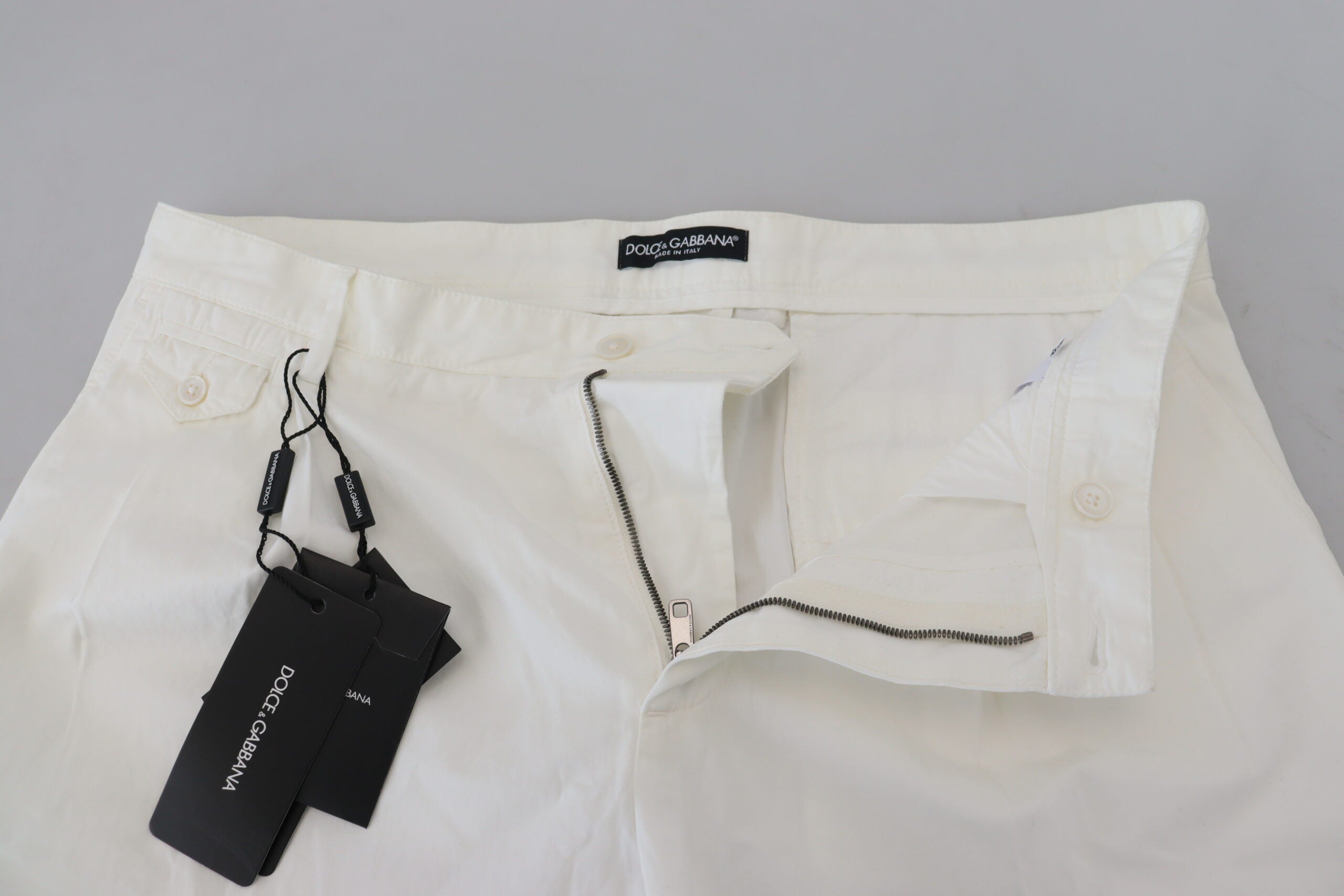 White cotton skinny chino pants by Dolce & Gabbana, shown with a close-up of the fitted waist and sleek fabric texture.