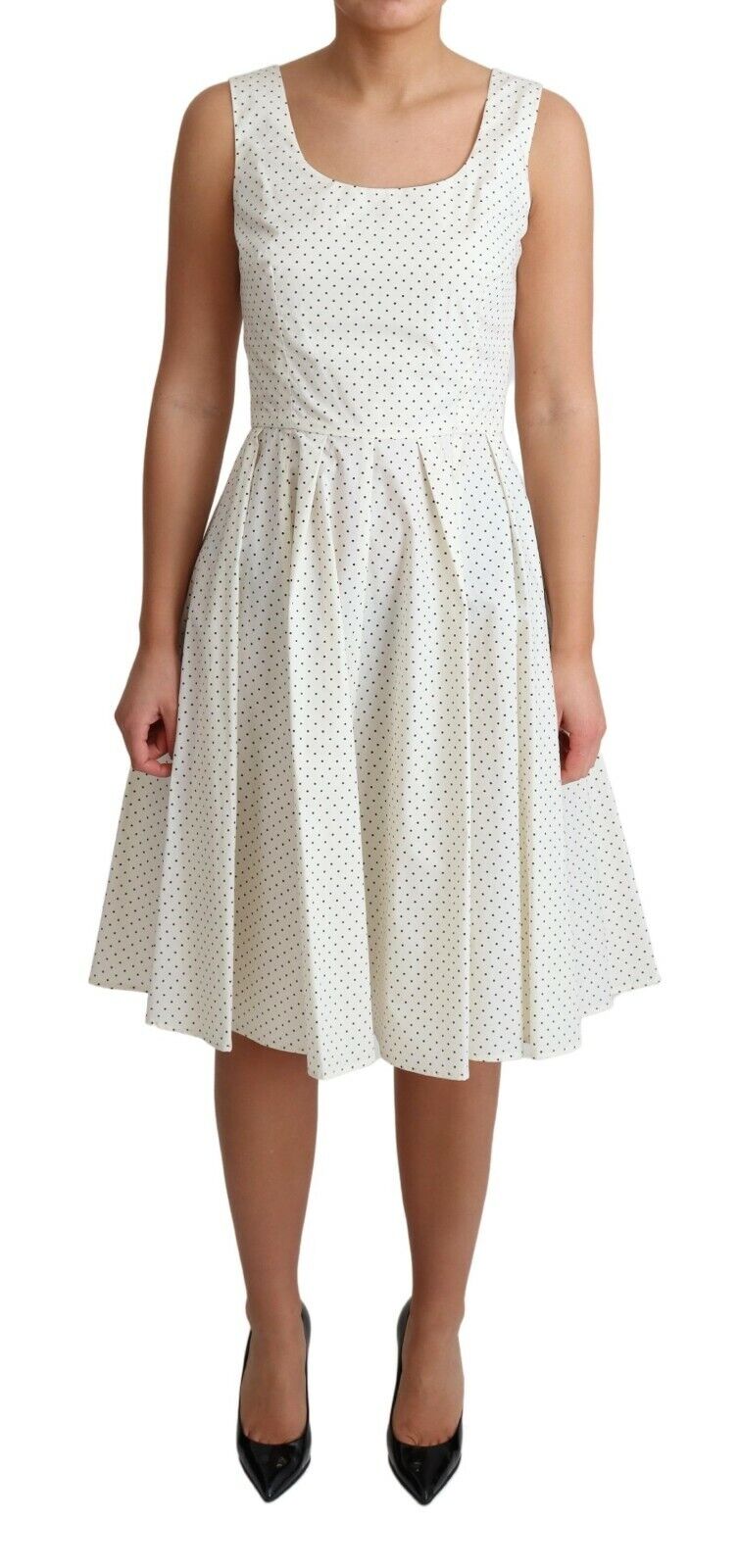 White polka dotted cotton A-line dress by Dolce & Gabbana hanging on a clothing rack with floral background.