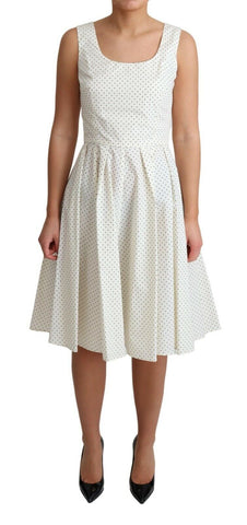 White polka dotted cotton A-line dress by Dolce & Gabbana hanging on a clothing rack with floral background.
