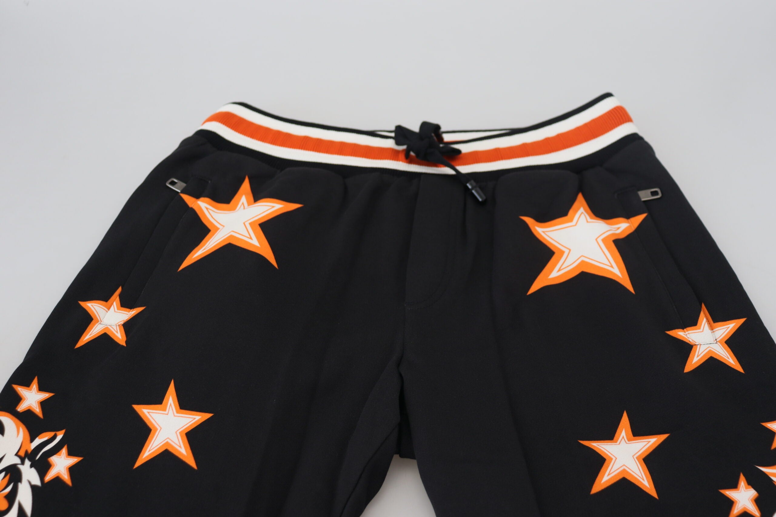 Black and orange star-patterned Dolce & Gabbana sport trousers, athletic pants with bold star design, relaxed fit, and comfortable fabric.