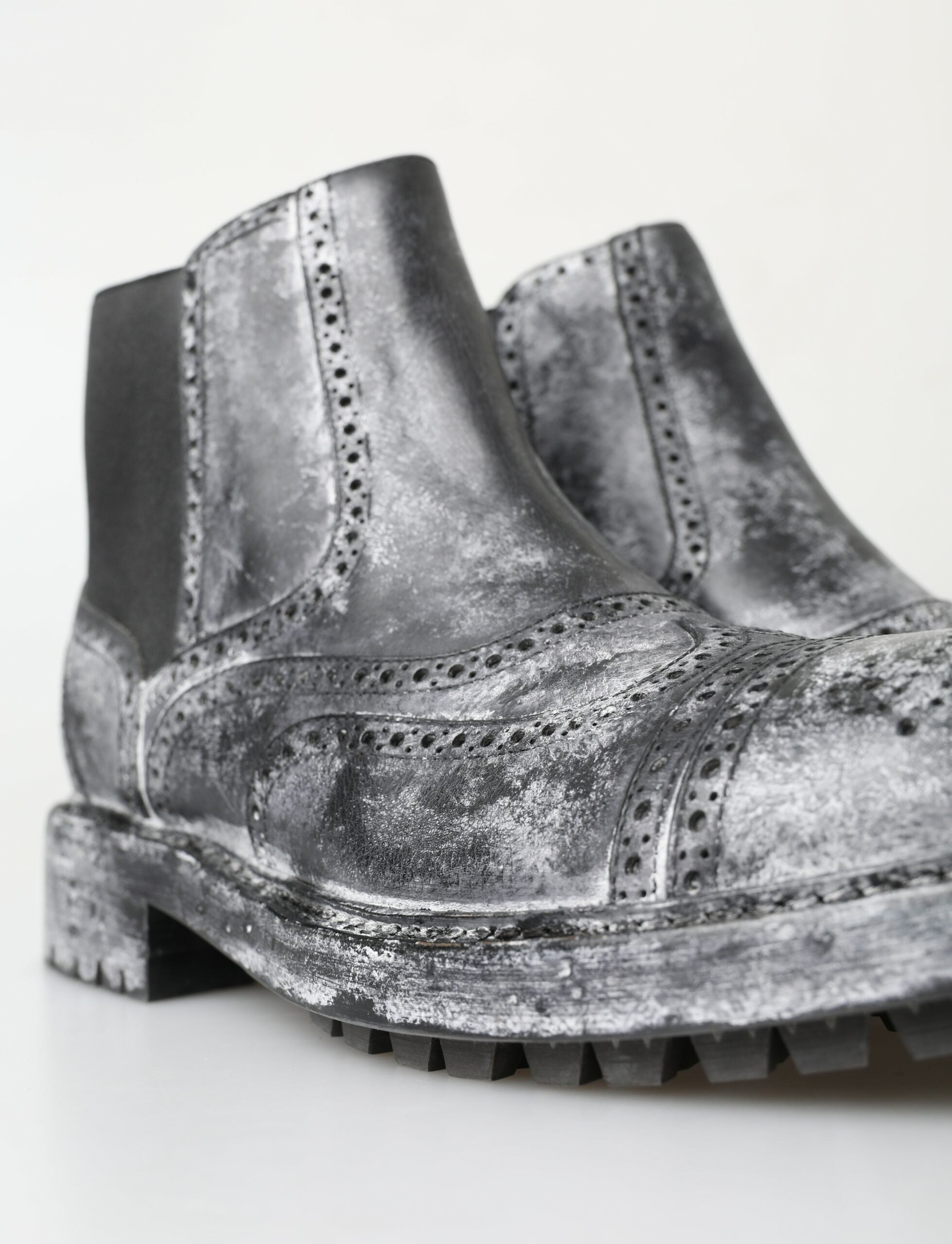 Black and gray leather ankle boots by Dolce & Gabbana with sleek design and pointed toes, shown in a close-up image.