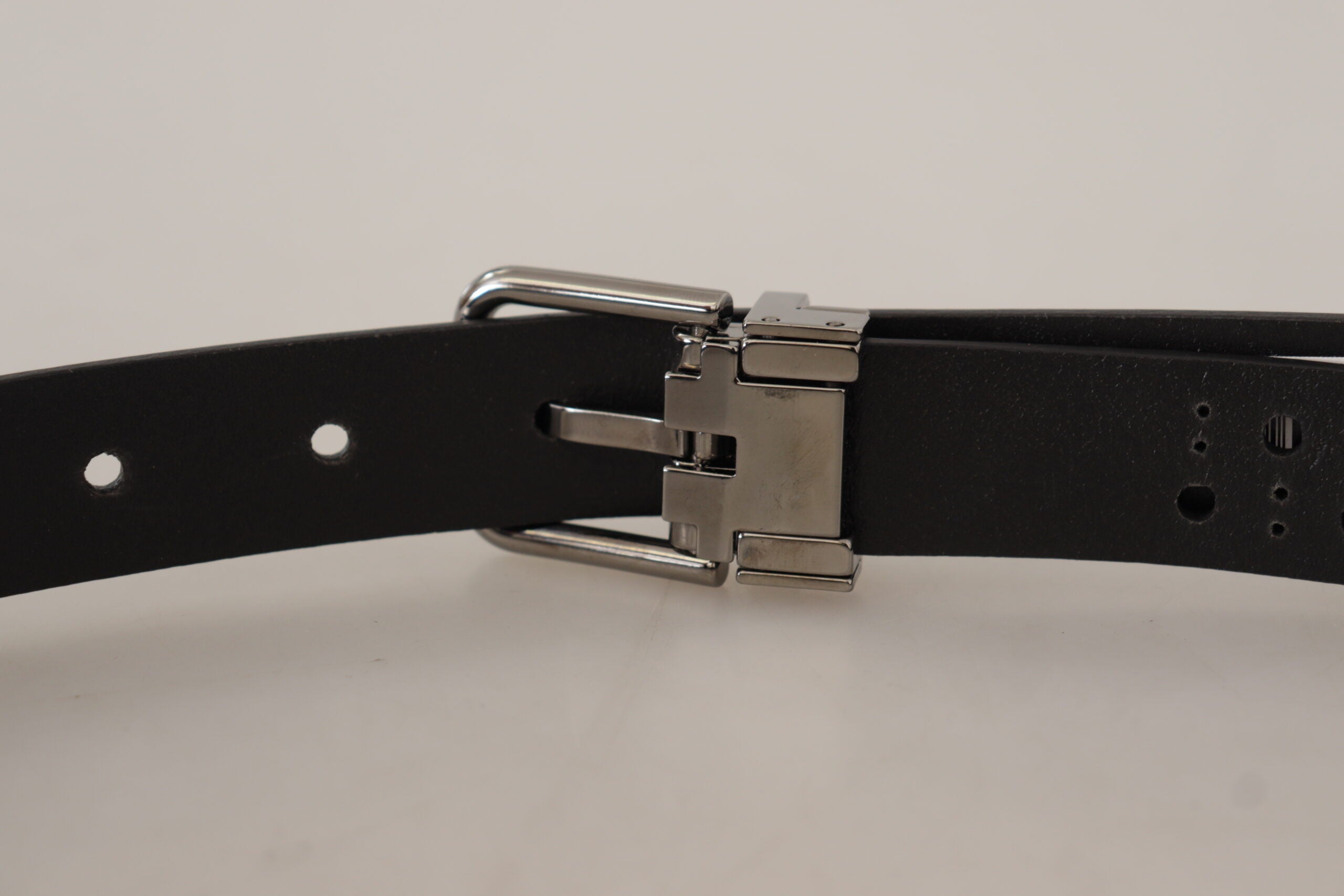 Black calf leather belt with perforated design and metal buckle by Dolce & Gabbana, displayed on a neutral background.