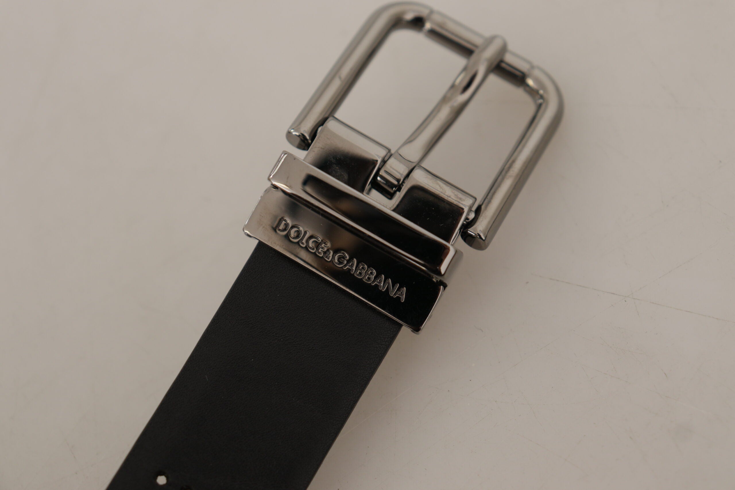 Black calf leather belt with perforated design and metal buckle from Dolce & Gabbana, showcasing its stylish craftsmanship.