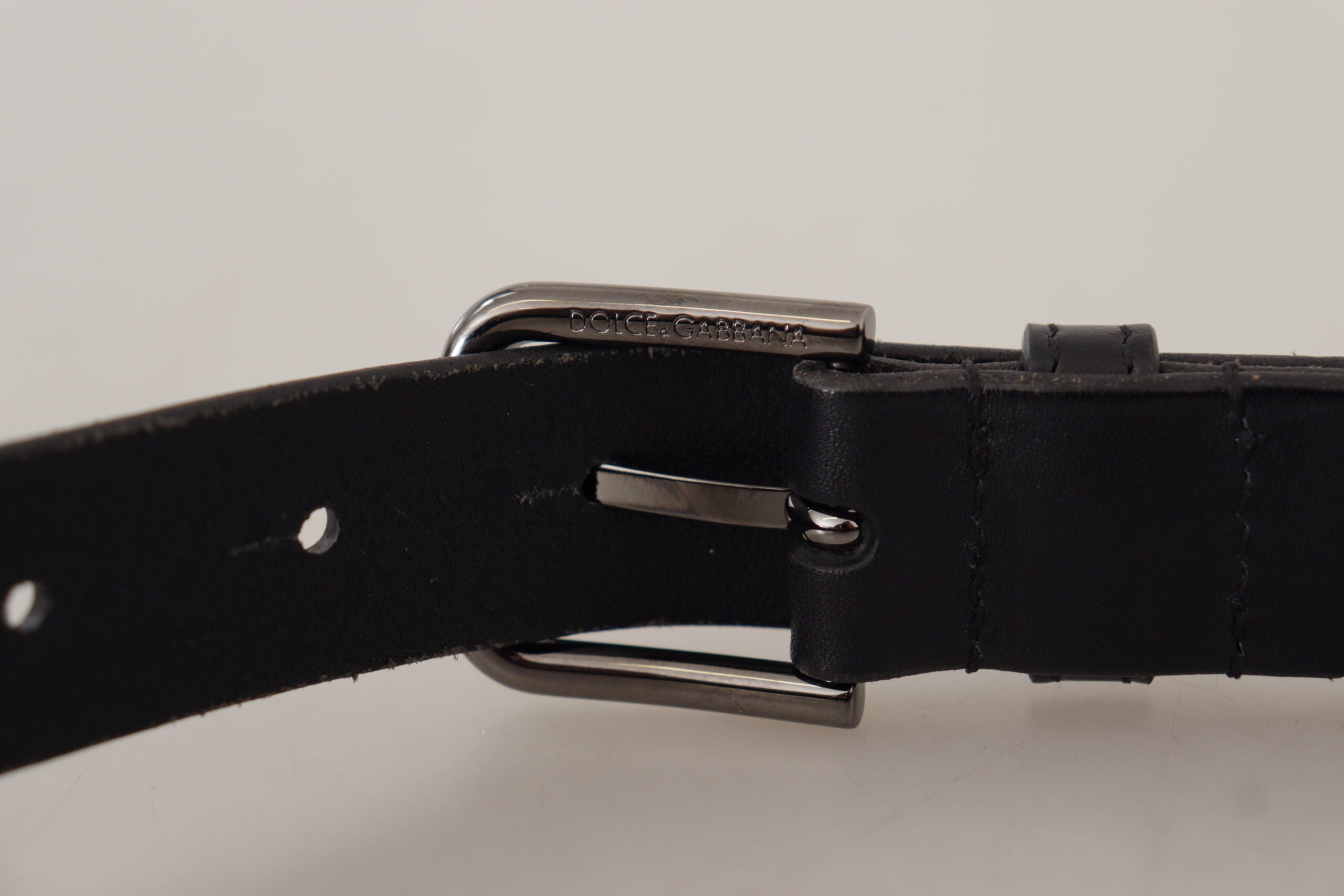 Black calf leather belt with engraved logo metal buckle by Dolce & Gabbana, showing detailed craftsmanship and sleek design.