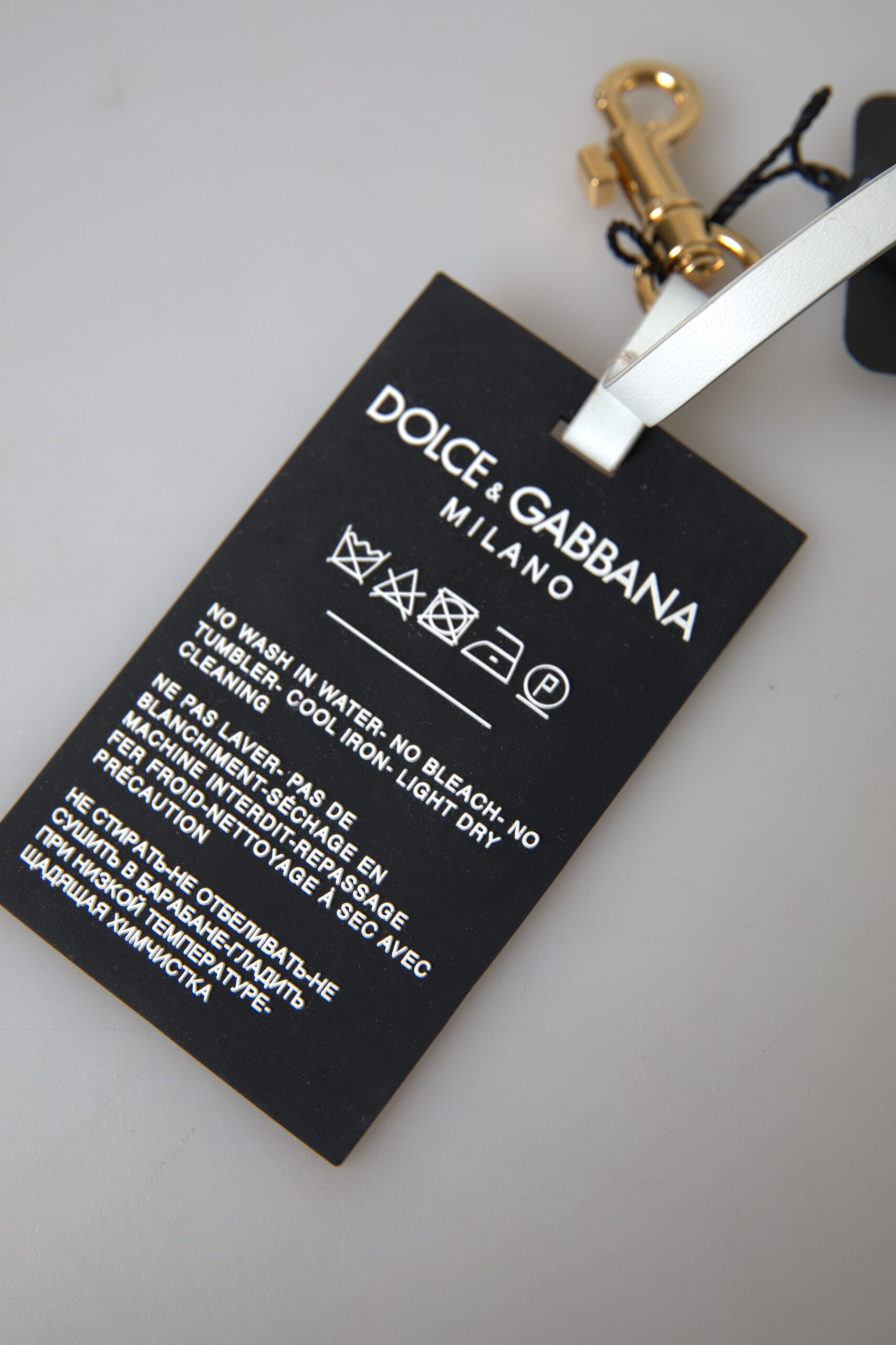 Black silicone keychain with gold brass Dolce & Gabbana DG logo, featuring a sleek and stylish accessory with brand emblem.