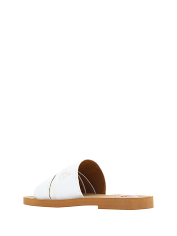 White cotton slides by Chloé featuring woody sandal soles, suitable for casual and stylish summer wear.