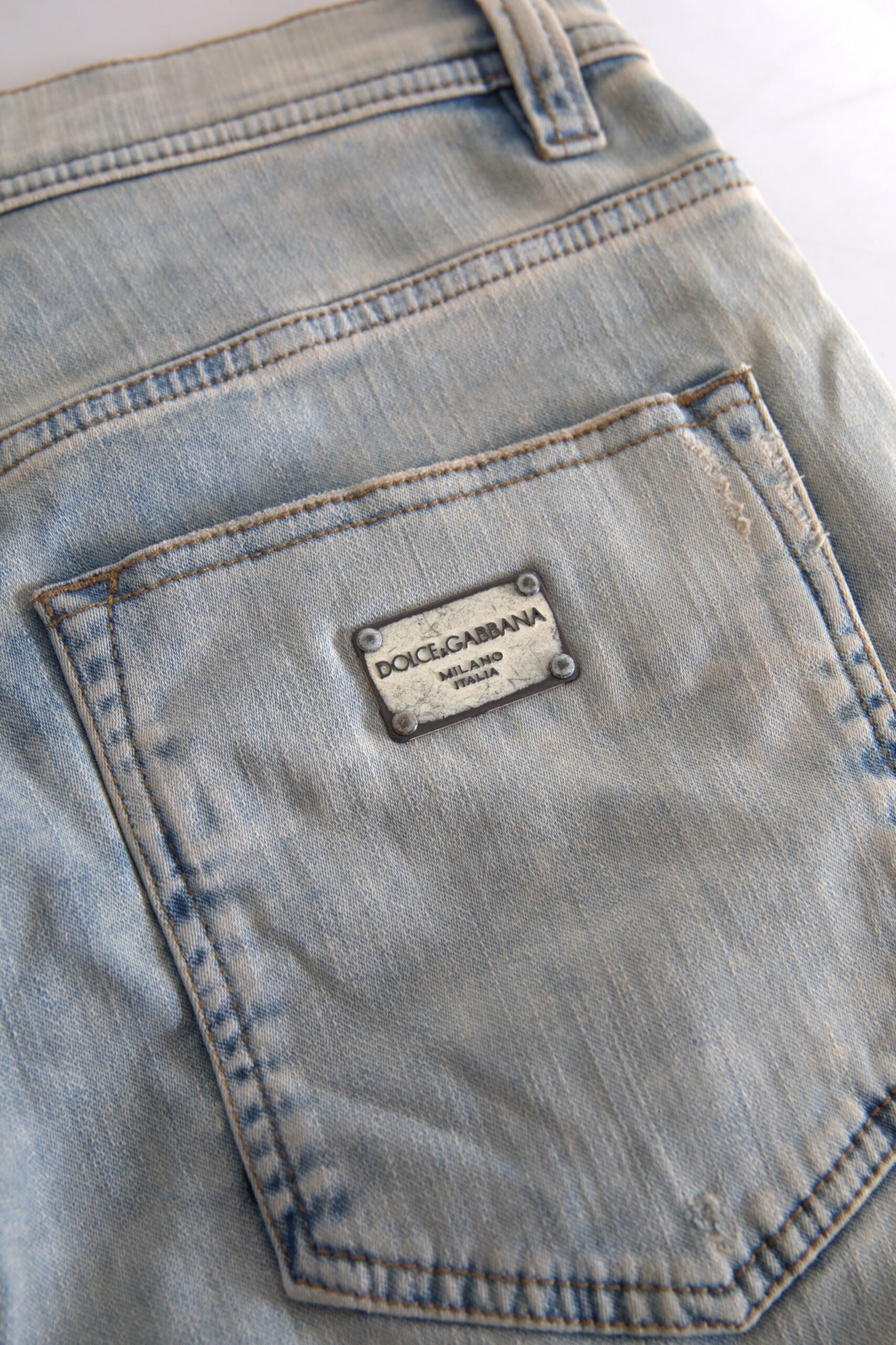 Blue washed cotton skinny jeans with mid waist from Dolce & Gabbana, shown hanging on a wooden rack.