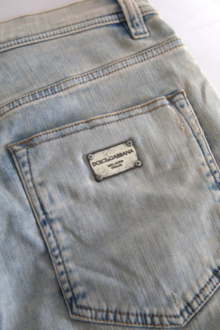 Blue washed cotton skinny jeans with mid waist from Dolce & Gabbana, shown hanging on a wooden rack.