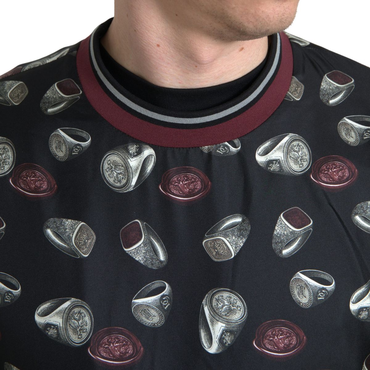 Dolce & Gabbana black silk crewneck sweater with ring print design, close-up showing the detailed pattern and soft fabric texture.