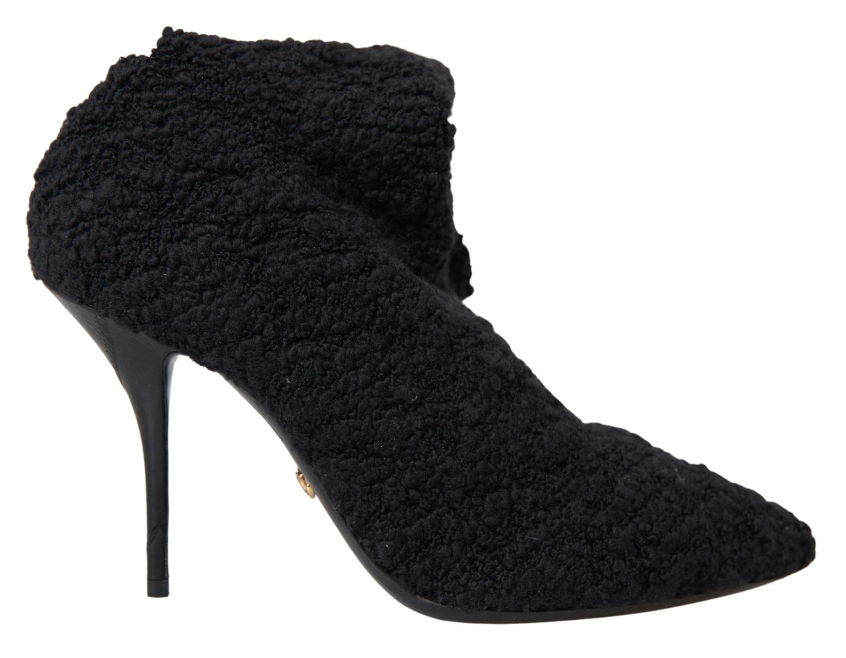 Black Dolce & Gabbana stiletto heels and mid-calf boots with sleek design and pointed toes on a plain background.