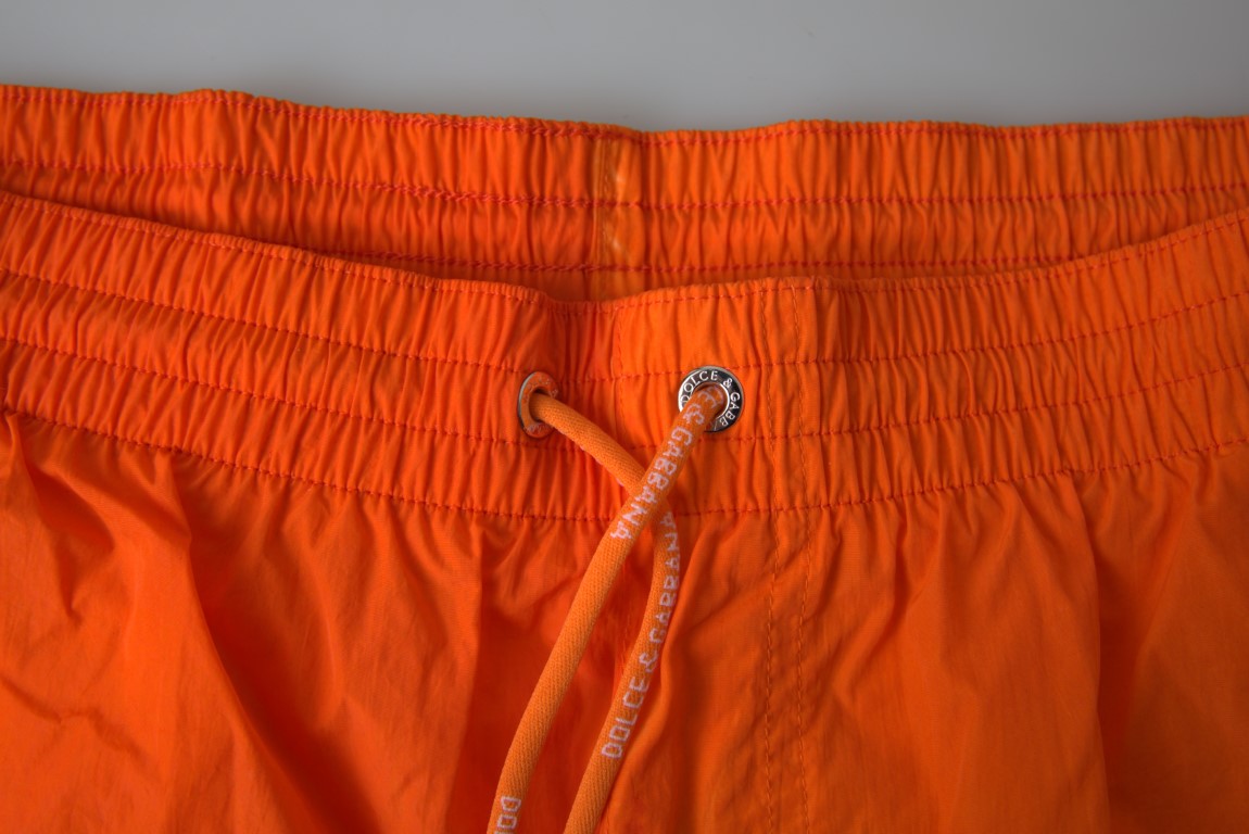 Orange and blue gradient Dolce & Gabbana beachwear swimwear shorts displayed on a model.