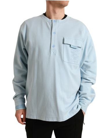 Light blue cotton buttoned pullover sweater by Dolce & Gabbana, shown on a hanger with detailed fabric texture.