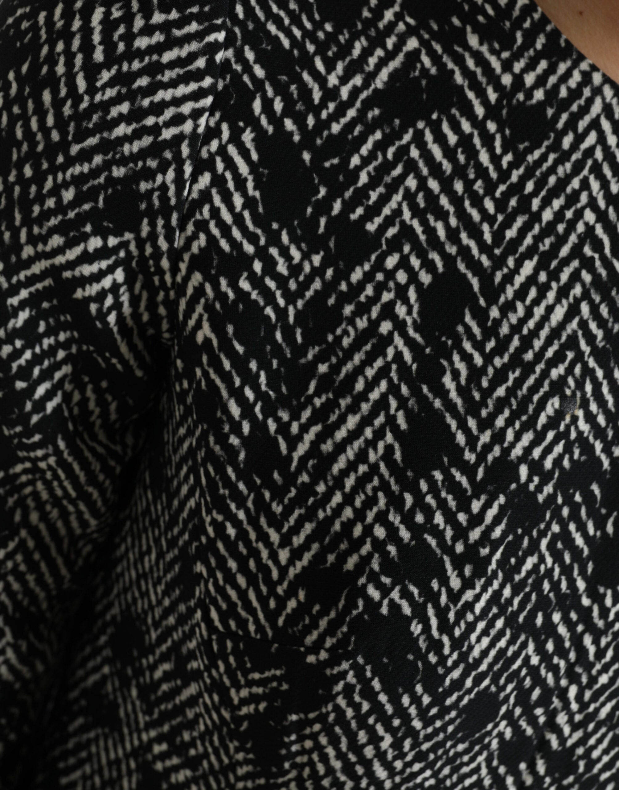 Black chevron polyester shift mini dress by Dolce & Gabbana hanging on a clothing rack, showcasing its stylish pattern and fit.