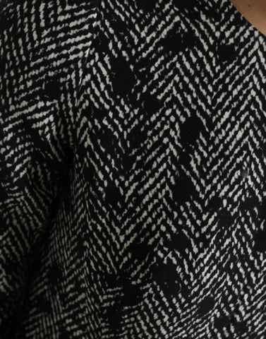 Black chevron polyester shift mini dress by Dolce & Gabbana hanging on a clothing rack, showcasing its stylish pattern and fit.