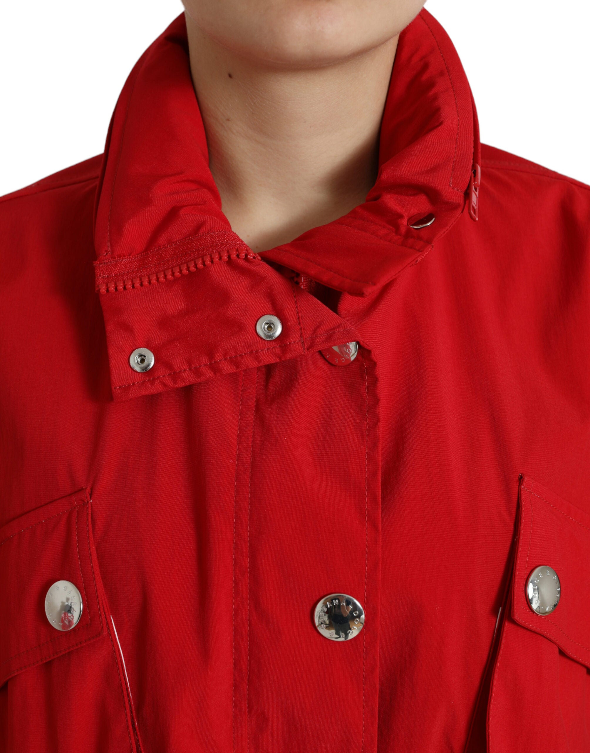 Red polyester hooded rain coat with button closure from Dolce & Gabbana, shown hanging outdoors.