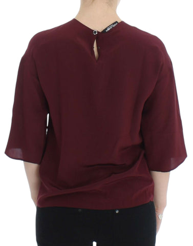 Red 3/4 sleeve silk blouse by Dolce & Gabbana displayed on a hanger with detailed fabric texture.