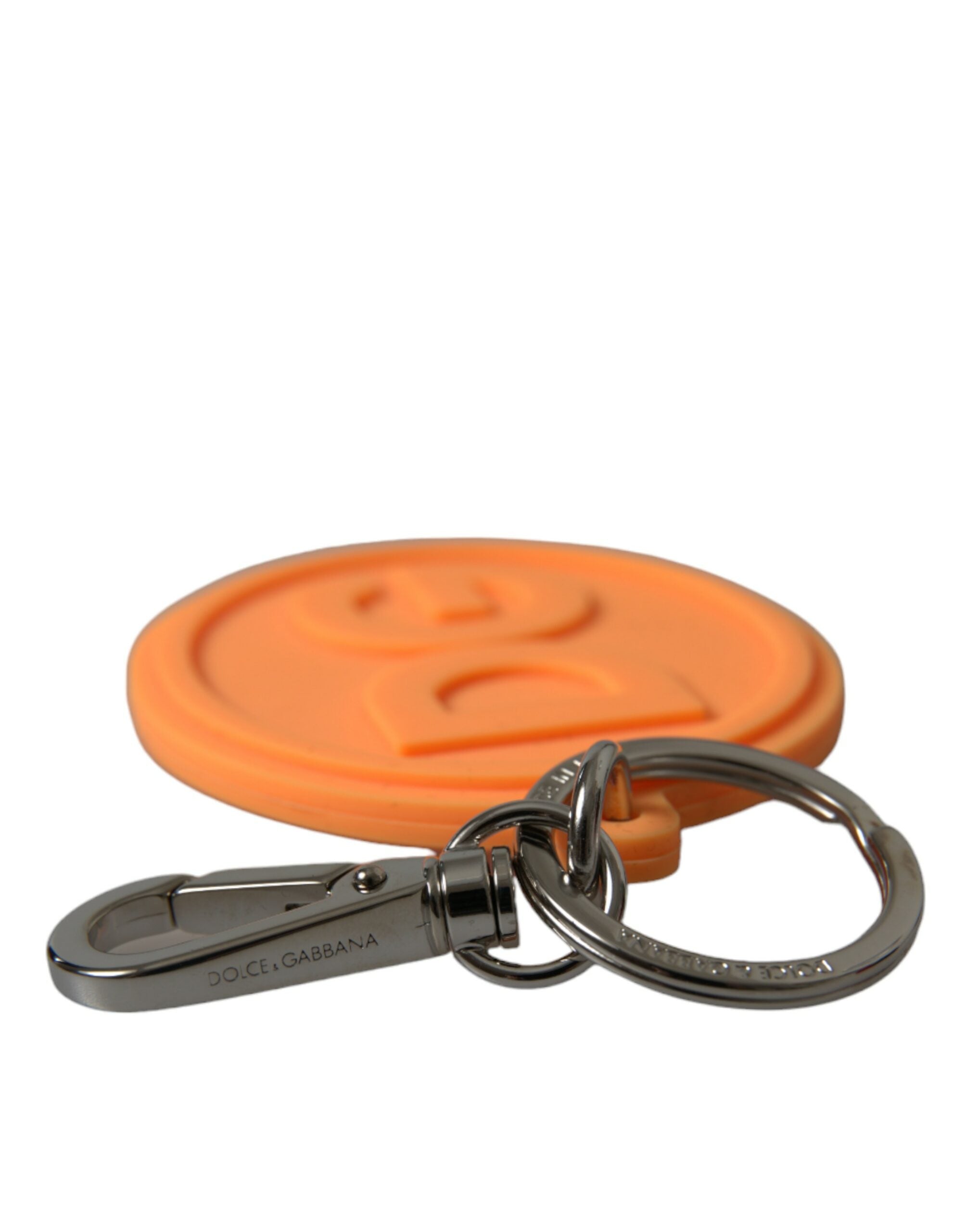 Orange rubber Dolce & Gabbana keyring with silver brass DG logo, metal keychain with textured finish and branding details.