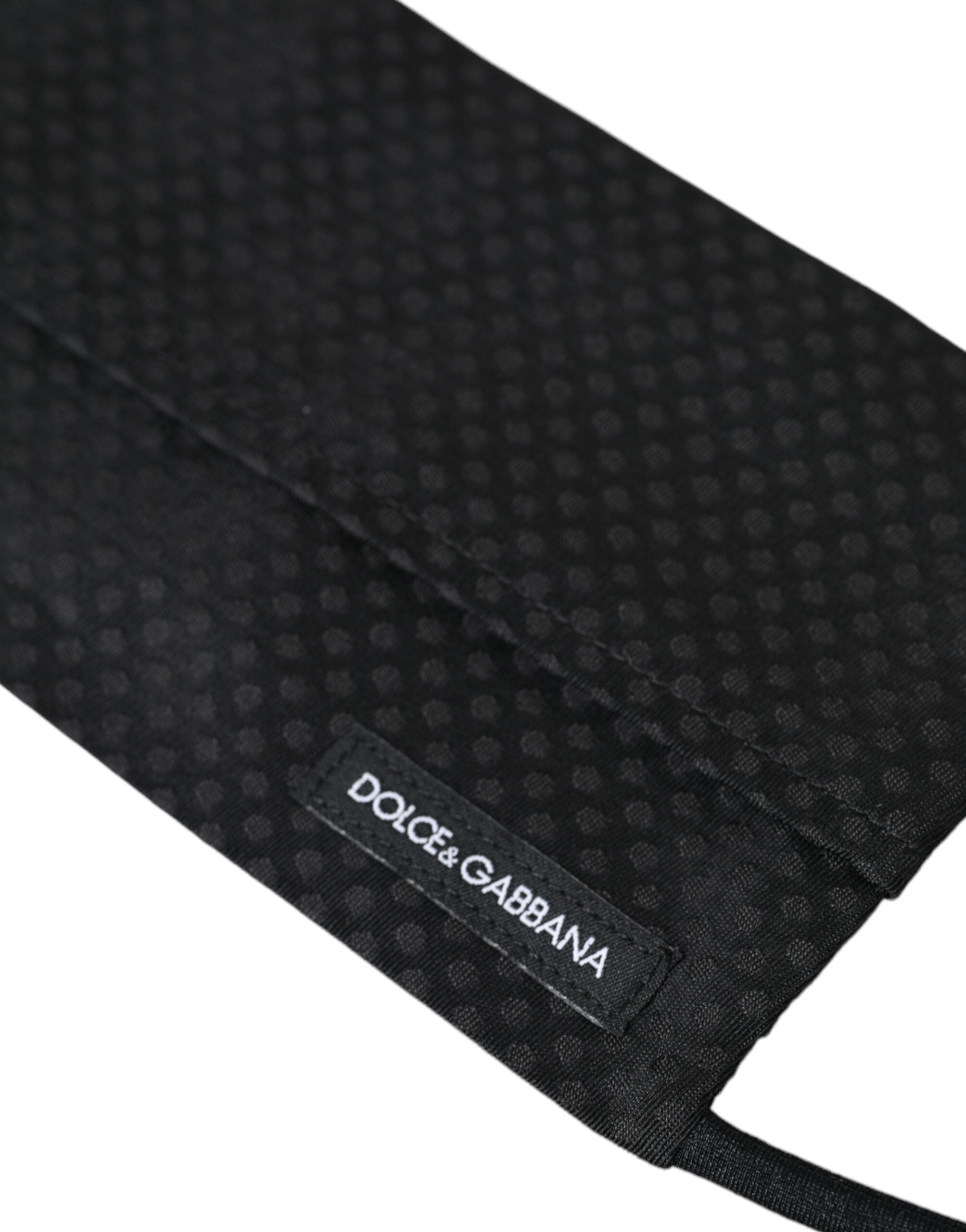 Black 100% silk adjustable necktie face mask by Dolce & Gabbana, featuring smooth silk fabric and adjustable straps.