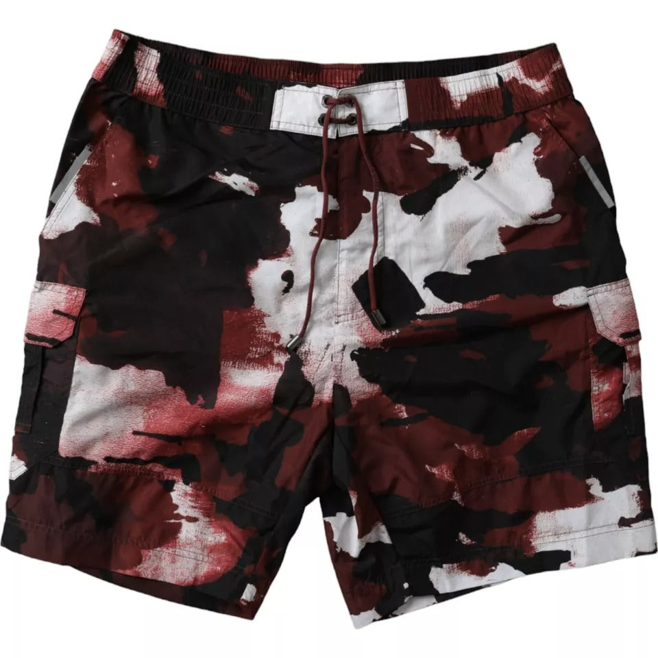 Multicolor camouflage Dolce & Gabbana logo beachwear shorts swimwear displayed on model with vibrant print and stylish design.