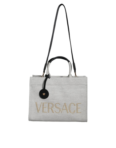 White Versace crossbody tote bag with top handles, canvas and leather construction, featuring the brand logo and spacious interior.