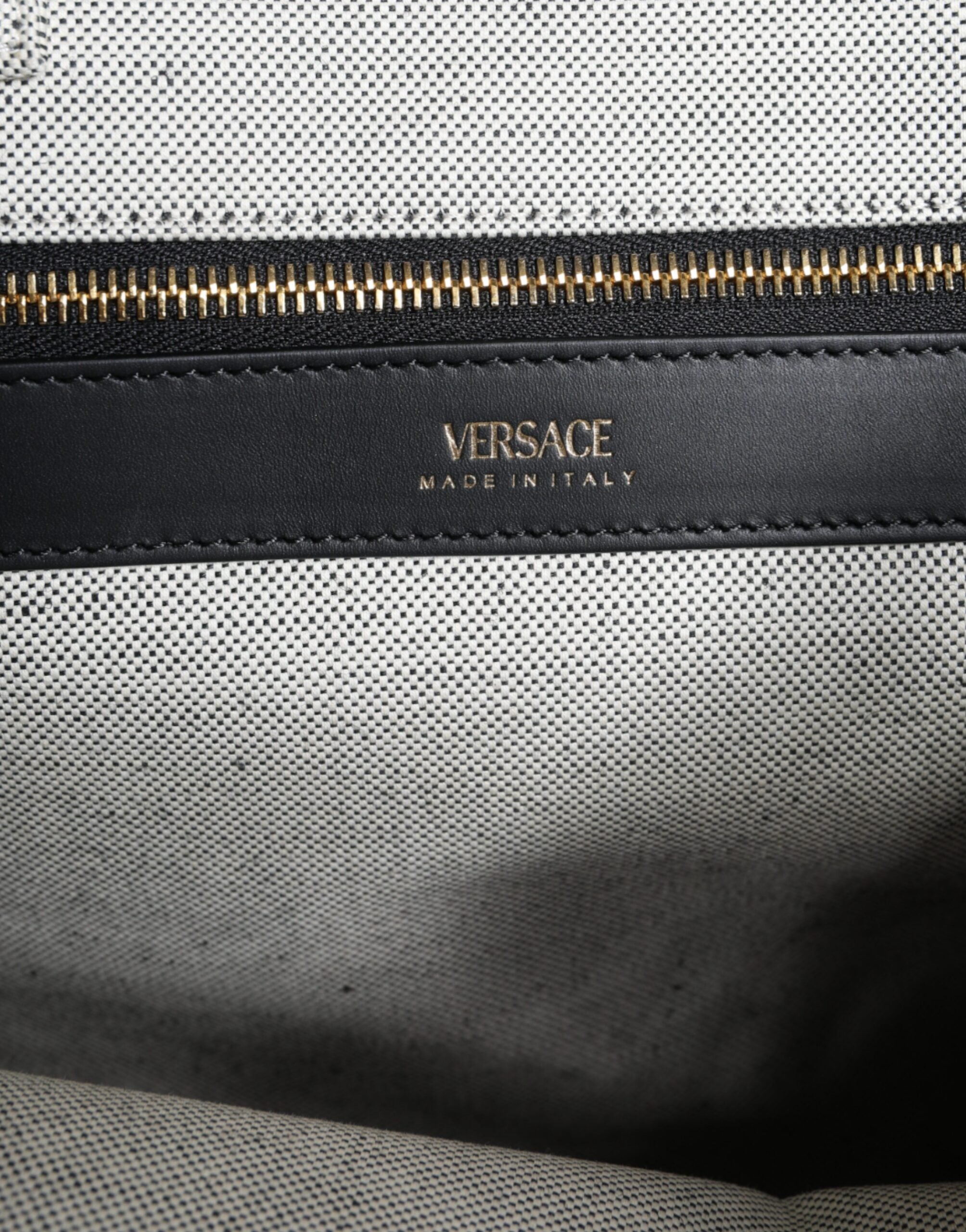 White Versace top handle canvas and leather logo crossbody tote bag with structured design and adjustable shoulder strap.