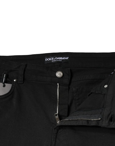 Black cotton stretch skinny denim jeans by Dolce & Gabbana, shown on a hanger with a close-up of fabric and fit details.