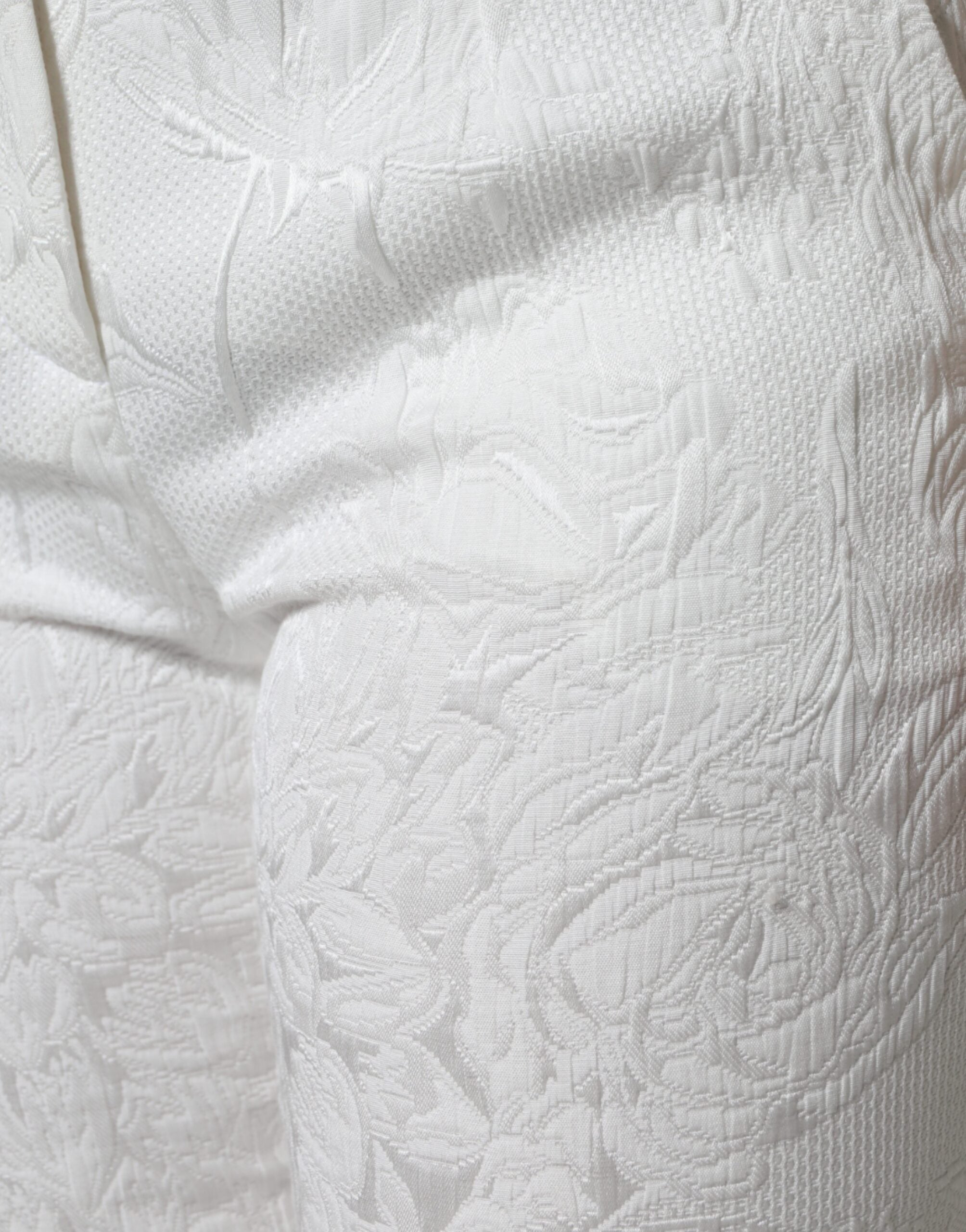 White floral brocade cotton cropped pants by Dolce & Gabbana with intricate floral pattern and tailored fit.