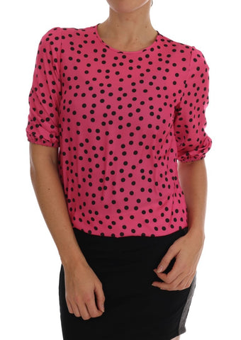 Pink polka dotted silk blouse by Dolce & Gabbana displayed on a hanger, showcasing its elegant design and vibrant pattern.