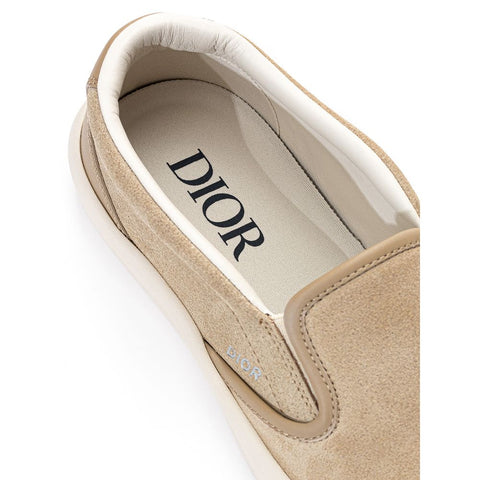 Dior beige leather slip-on loafers with smooth finish and classic design, showing the stylish footwear from a side angle.