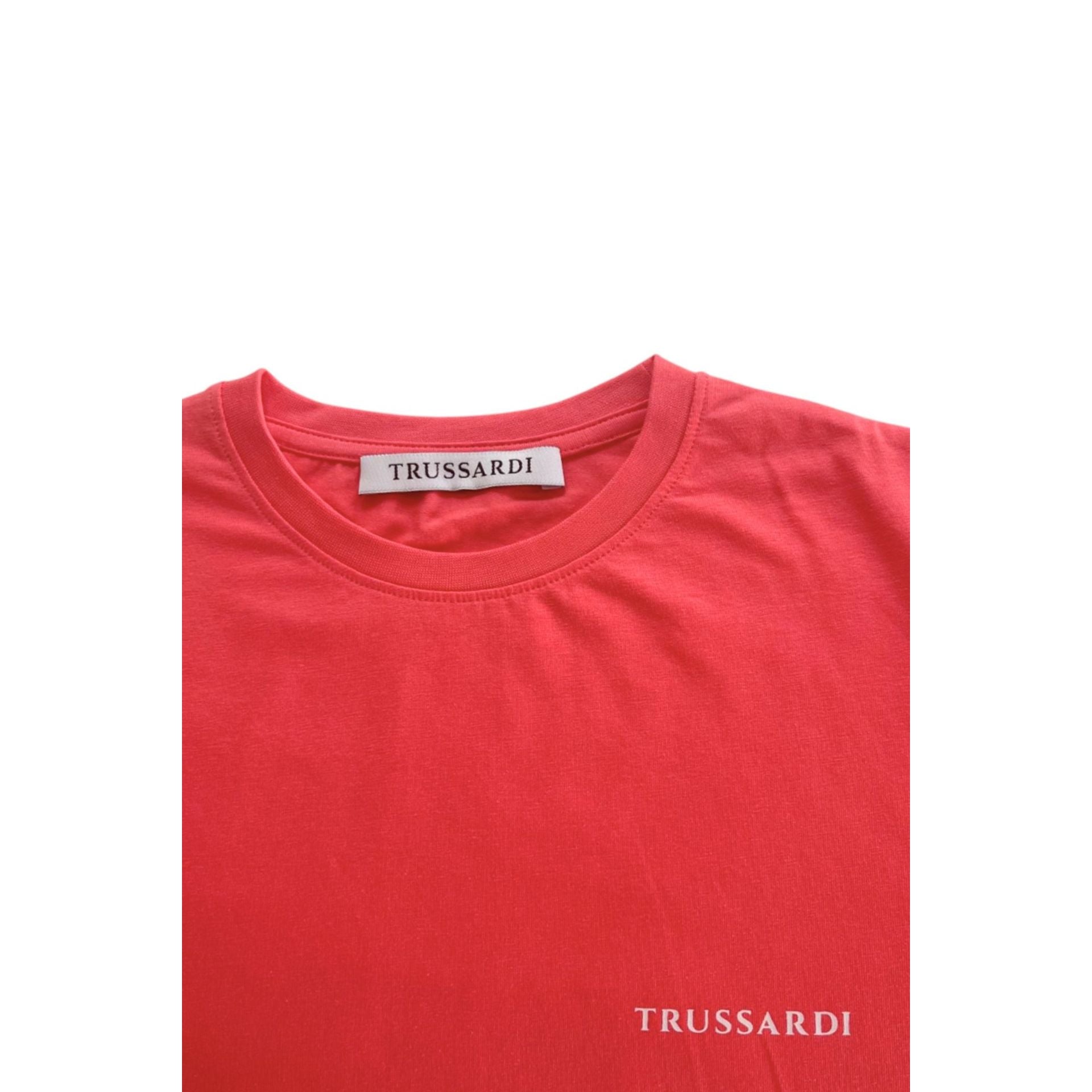 Trussardi beachwear in salmon color, featuring a stylish design, displayed on a model at the beach.