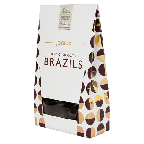 Dark chocolate coated Brazil nuts in a carton from Joybox by Jag Couture London New York, with visible nuts and chocolate coating.