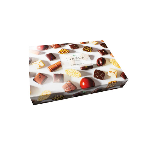 Assorted Jag Couture London New York pralines and chocolates with elegant wrapping and decorative toppings on a white plate.