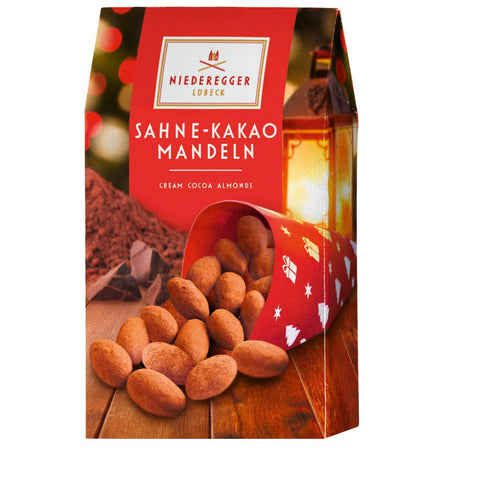 Cream cocoa-dusted almonds in a red gift carton from Jag Couture London - New York, displayed in an elegant container.