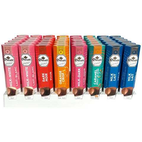 Assorted chocolate pastilles in a tube by Jag Couture London New York, displayed in a clear container with colorful chocolates inside.
