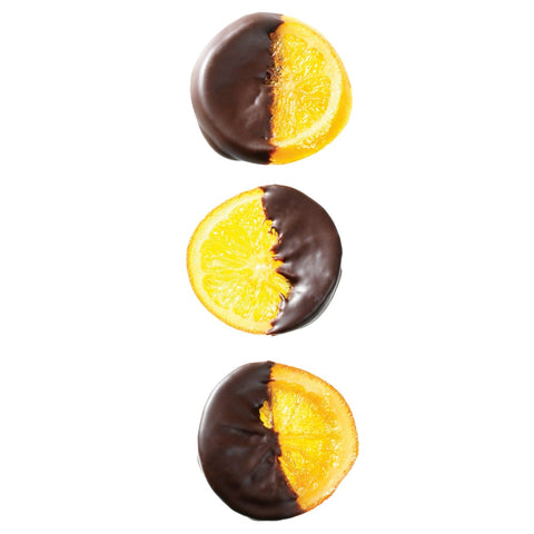 Half-dipped orange slices in dark chocolate from Jag Couture London - New York, showcasing fresh citrus and rich chocolate coating.